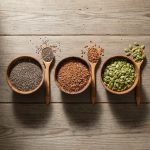 Organic chia, flax, and pumpkin seeds on a wooden table representing health benefits.